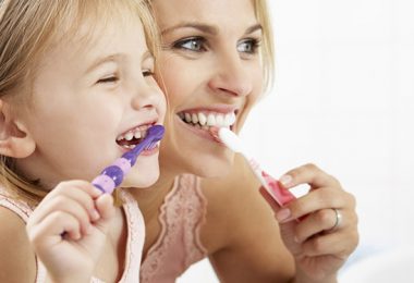 Mutter zeigt Tochter wie man Zähne richtig putzt