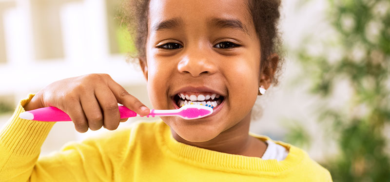 Mädchen putzt sich die Zähne mit fluoridhaltiger Zahnpasta