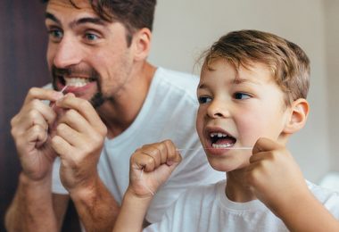 Vater und Sohn benutzen Zahnseide