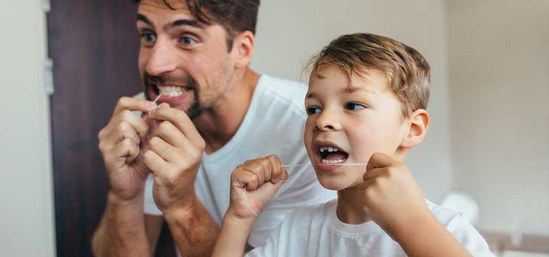 Vater und Sohn benutzen Zahnseide